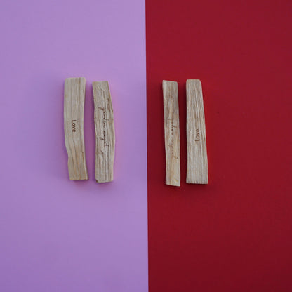 Rosa und roter Hintergrund. Auf jeder Farbe liegen jeweils zwei Palo Santo Sticks mit dem Mantra Love und umgekehrt mit dem yardin zayel Logo.